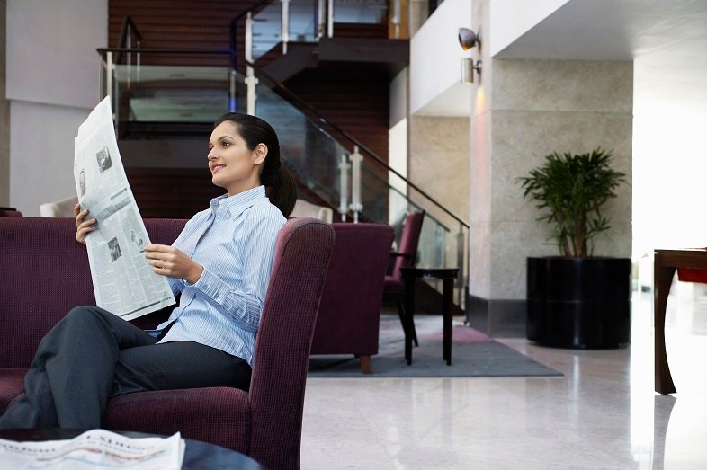 Business woman reading newspaper in hotel lobby